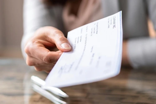 Hand holding a paycheck. 