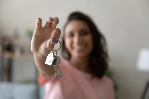 Woman holding up a set of house keys and smiling.