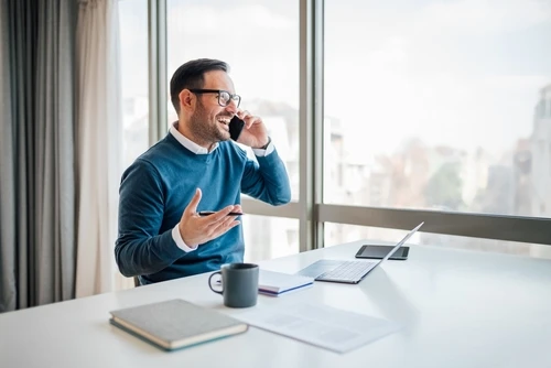 Landlord talks happily on the phone explaining what is rental verification to a potential tenant. 