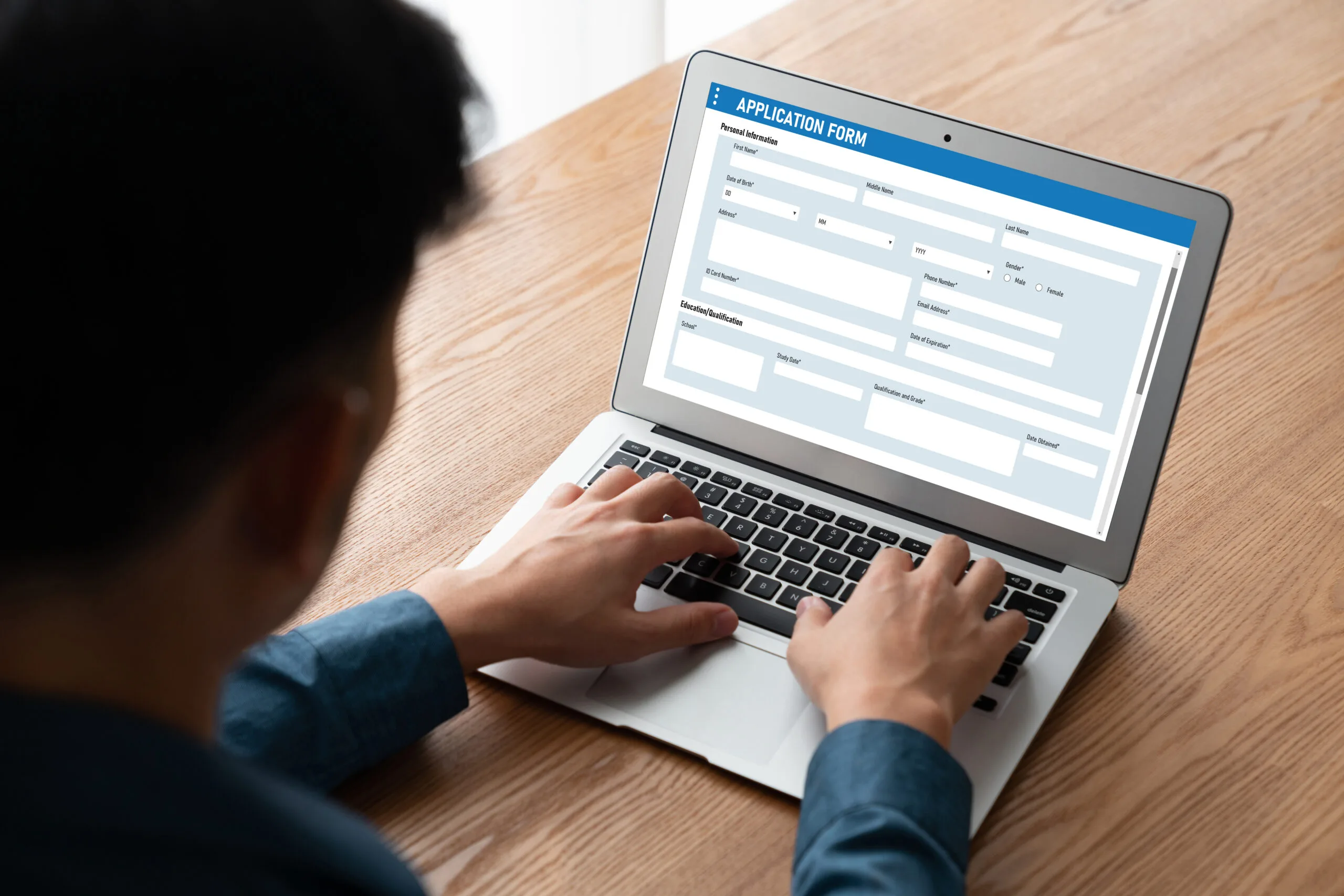 Man sits at desk filling out an online rental application on a laptop.
