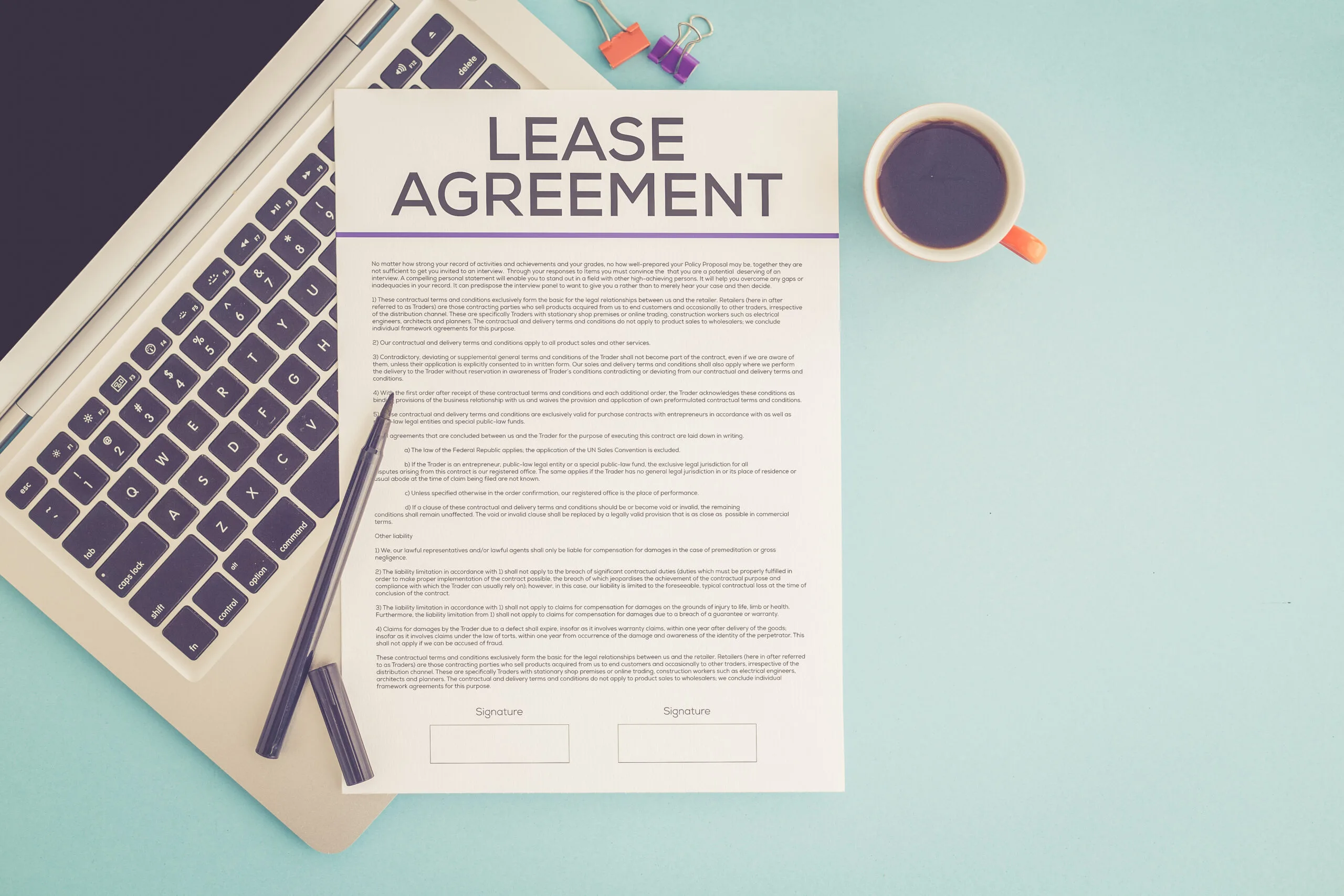 A paper titled "lease agreement" on top of a laptop