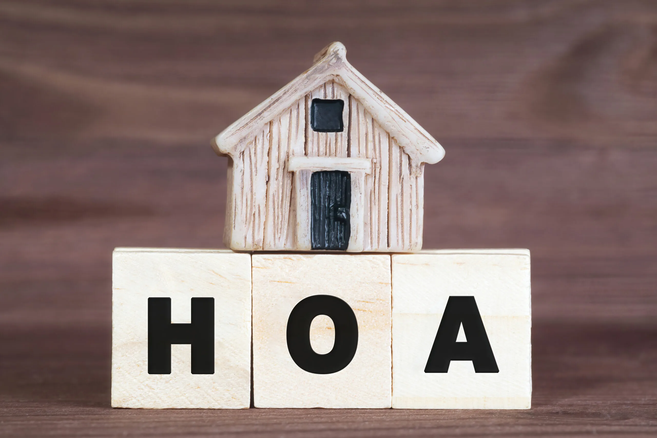 Abbreviation HOA made from wooden letter blocks with a miniature house on top. Homeowner association concept.
