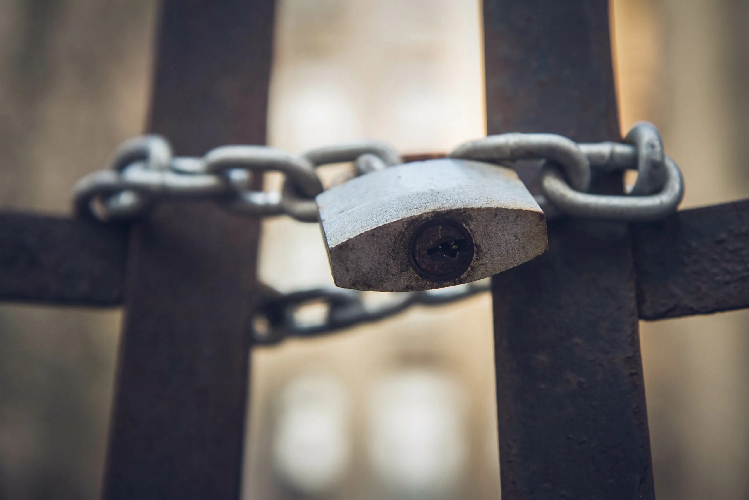Abandoned tenant house, with a gate closed with a padlock in the foreground - focus on the padlock