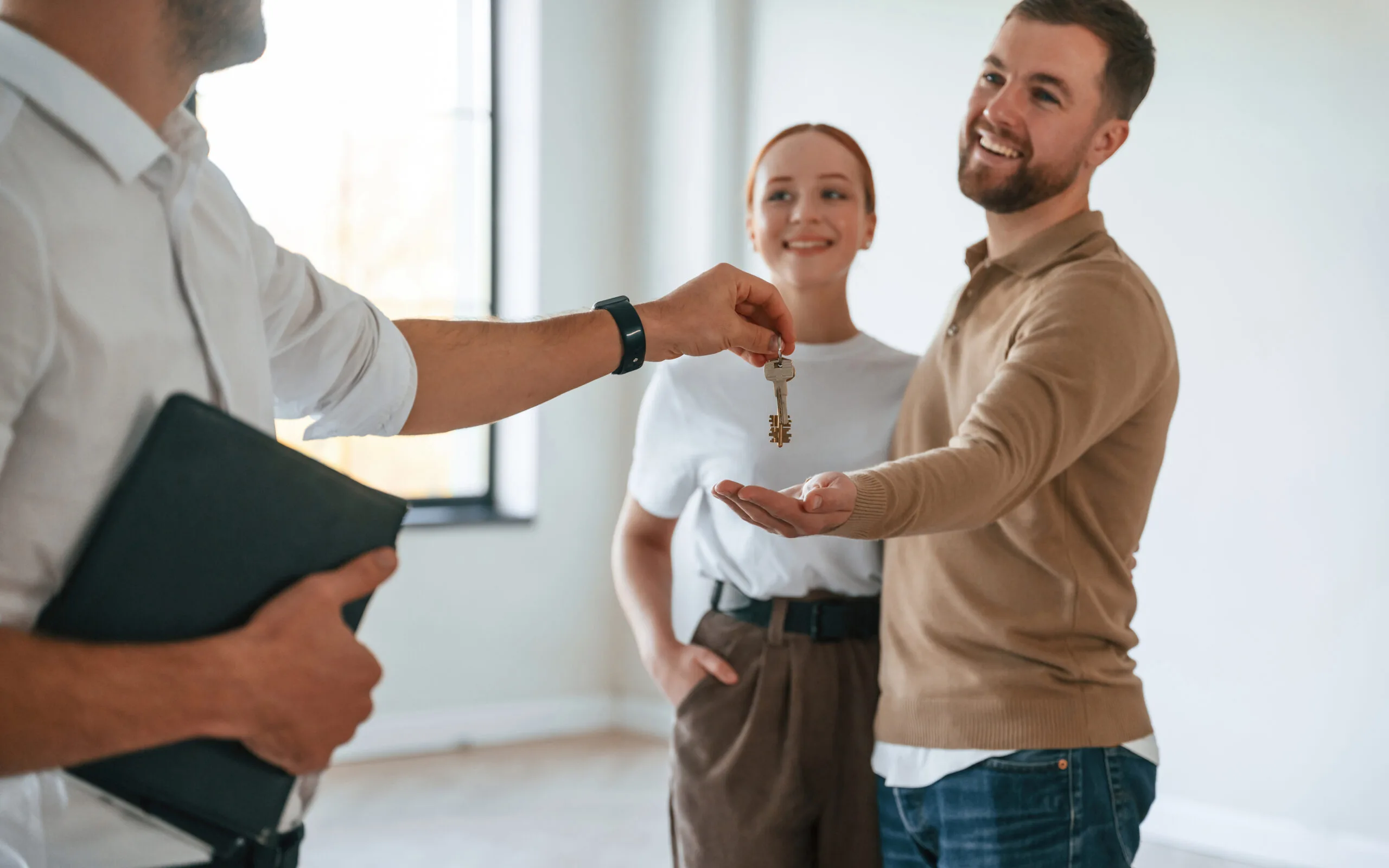 Living in an apartment, landlord hands over the keys to young couple.