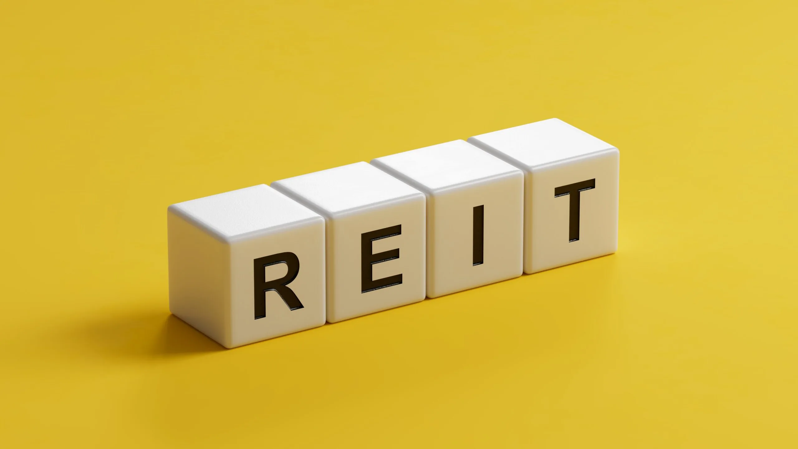 Word reit on wooden cubes with copy space.close up of wooden cubes,Business Concept.3D rendering on yellow background.