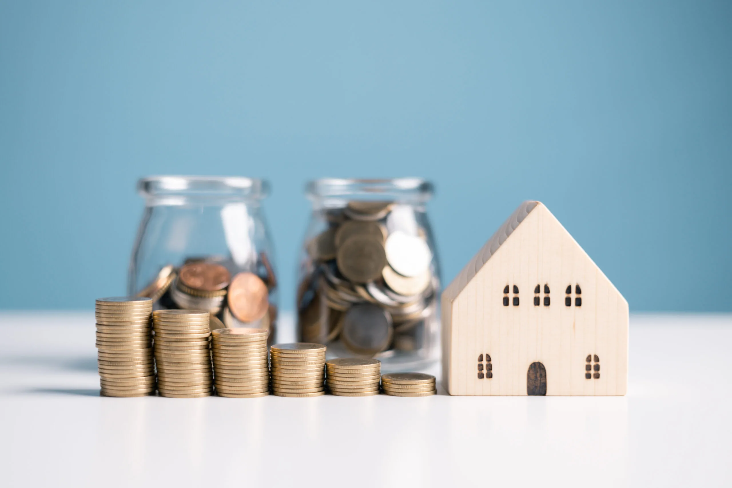 a wooden toy house next to two bottles with coins on it