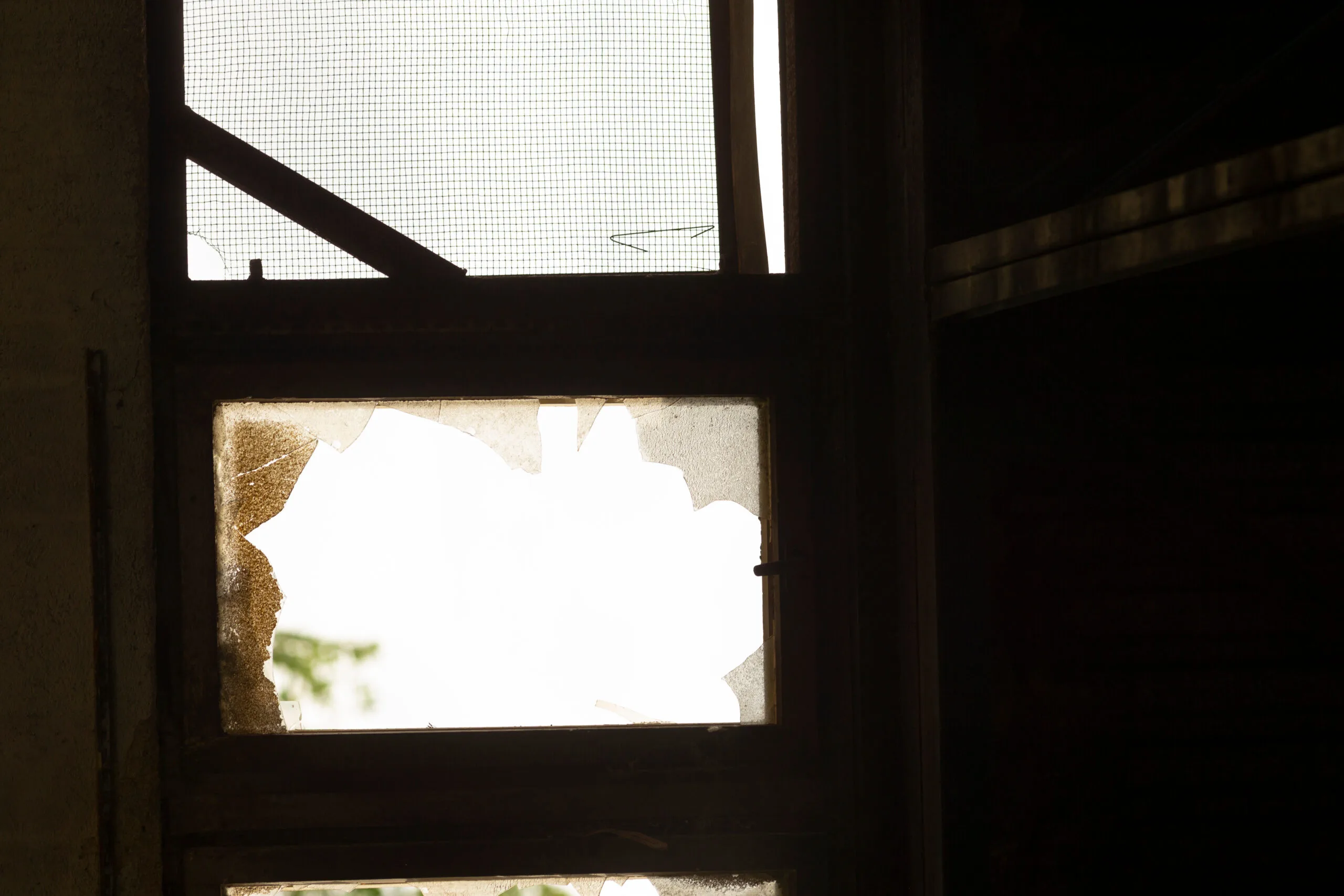 A broken window is present, and it has a mesh screen installed on it, which adds some texture and complexity to its appearance