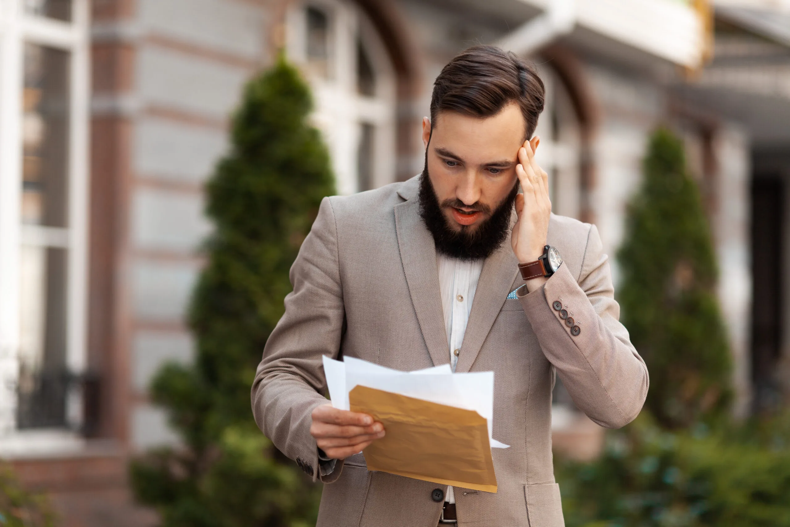 man holding his head in shock at a paper he's looking at