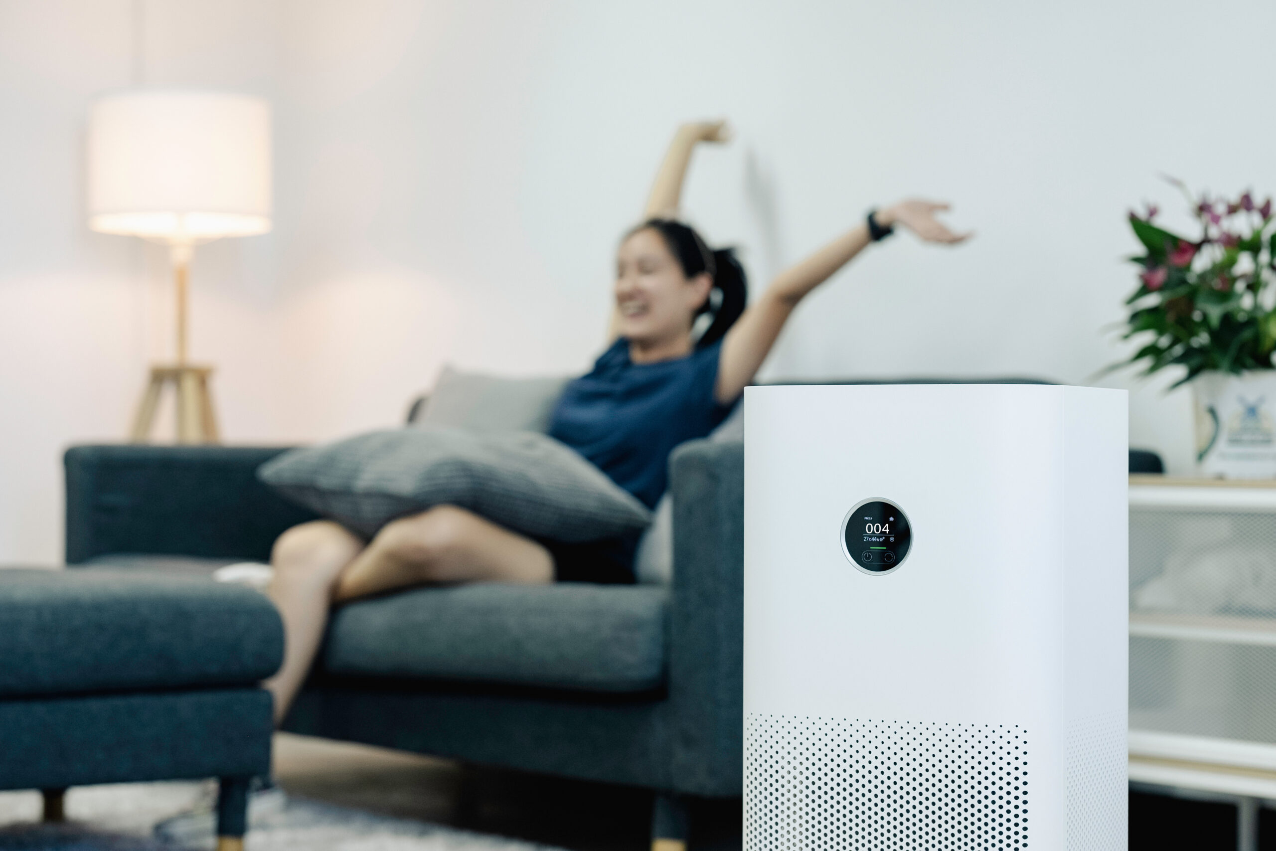 a woman hanging back and relaxing on her couch next to an air filter