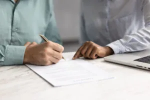 Close up view, man holding pen and signing lease or rental paper agreement, buying personal insurance coverage, committing to bank loan, credit line, or investment, accepting vendor or supplier terms