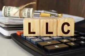llc for rental property in texas​, Finance and economics concept. On the table are money, a calculator, a notebook and cubes with the inscription - LLC
