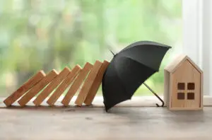 Umbrella Insurance vs Landlord Insurance, Umbrella protecting house from domino collapse, insurance concept