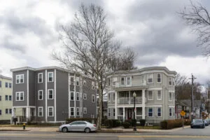 Residential street scene featuring modern and traditional multifamily homes under overcast sky, how to find multifamily properties​