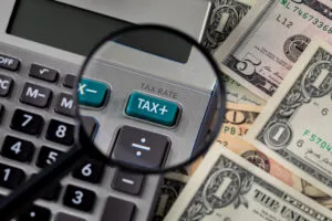 Tax calculator, magnifying glass and cash money. Income, sales and property taxes concept. | | Bay Management Group Texa