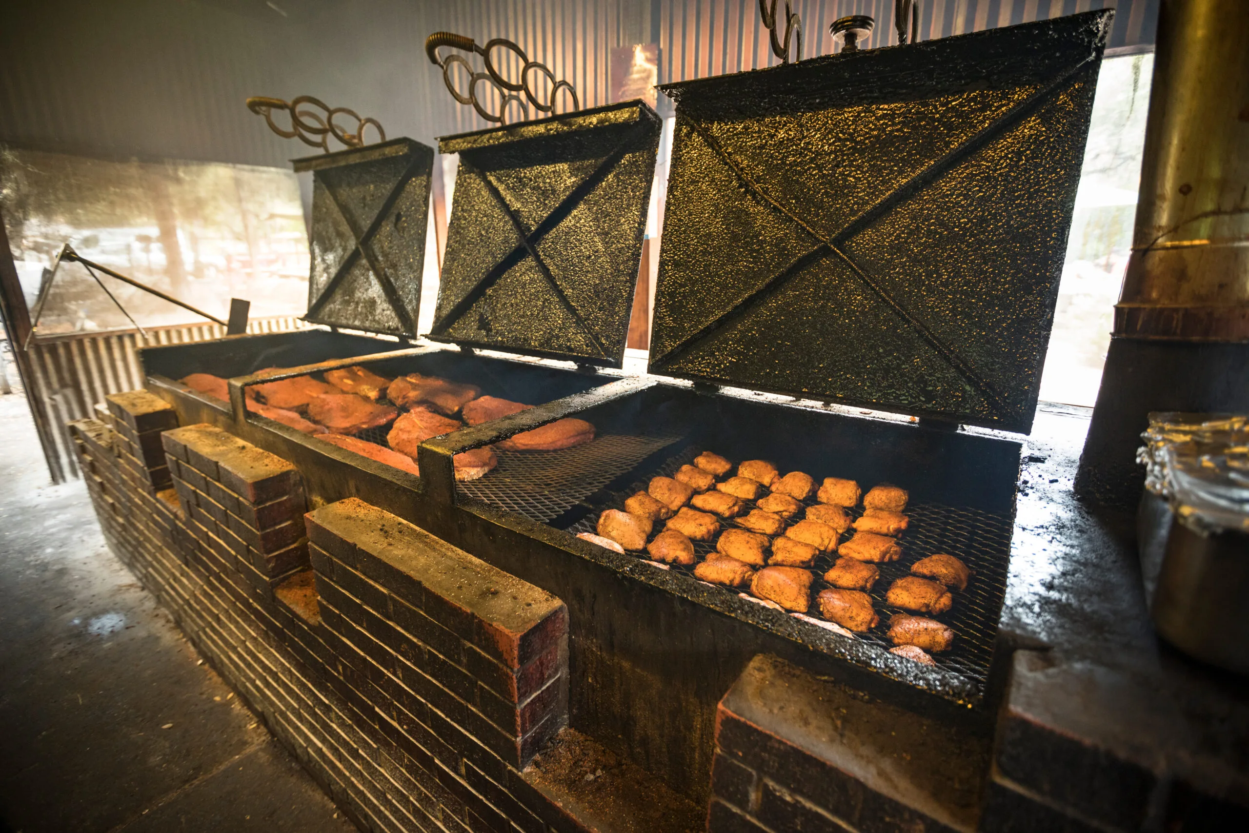 Large brick barbecue pit filled with smoking meats | Bay Management Group Texas