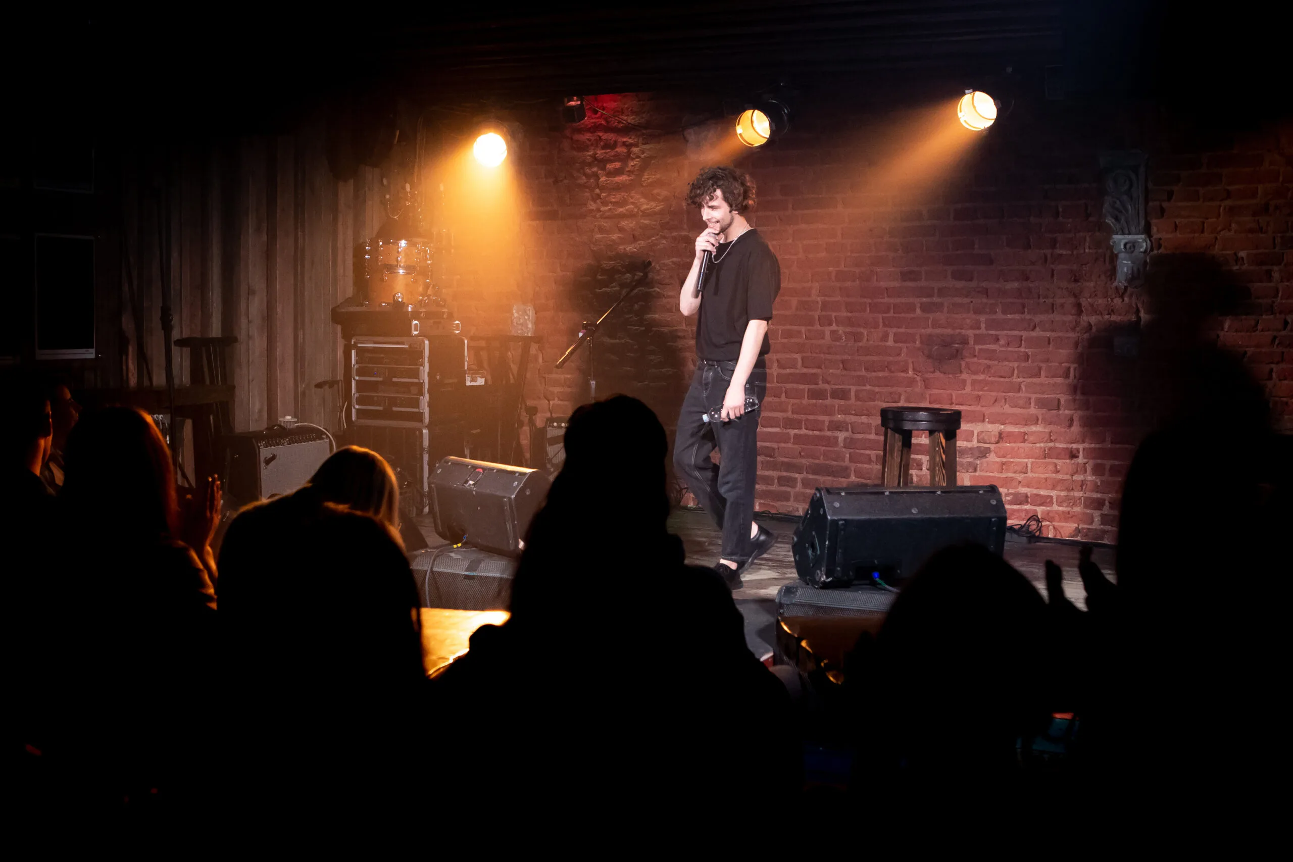 Young Caucasian male comedian performing his stand-up monologue on a stage of a small venue | Bay Property Management Gr