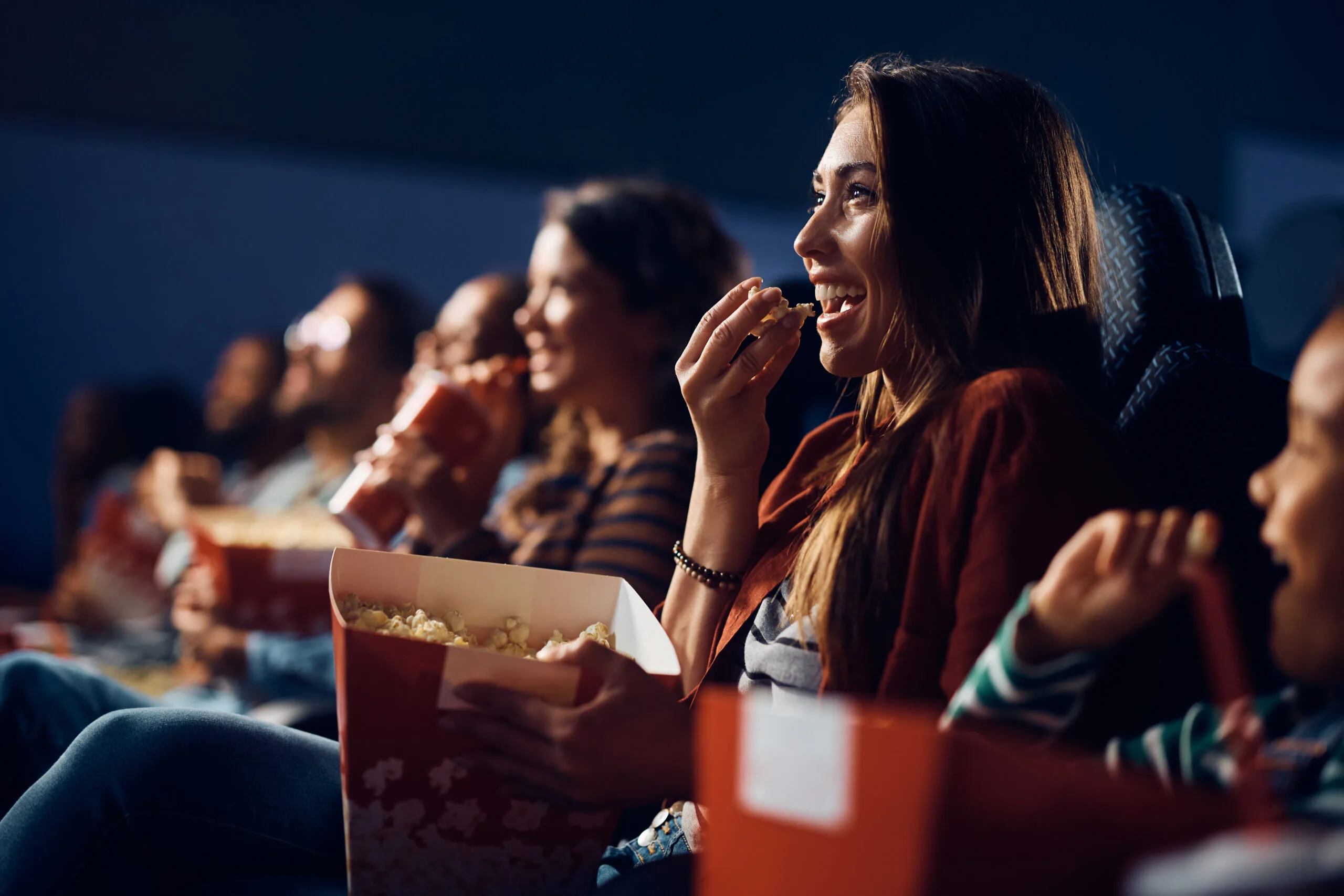 Cheerful woman eating popcorn during comedy movie in cinema. | Bay Property Management Group Texas
